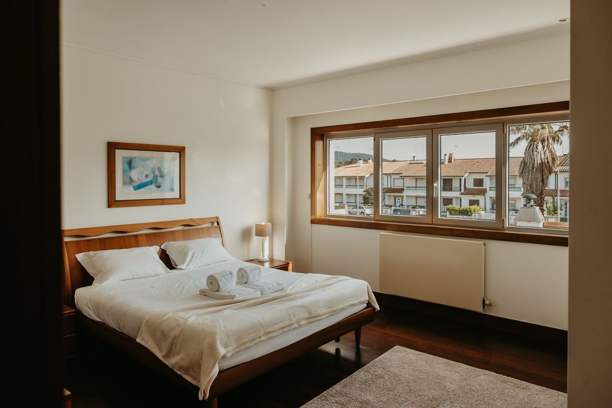 Quarto da moradia com cama preparada e roupa de cama branca