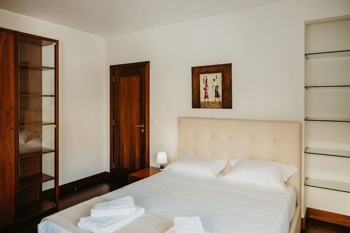 Quarto da moradia com cama preparada e roupa de cama branca