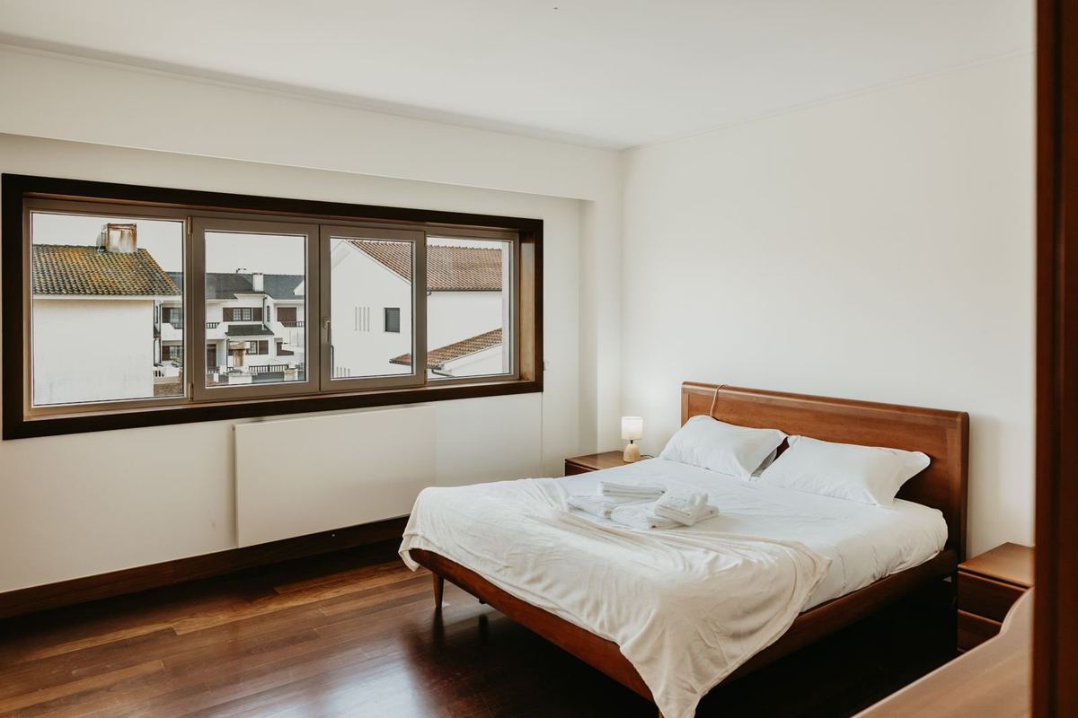 Quarto da moradia com cama preparada e roupa de cama branca