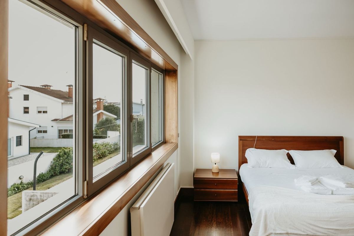 Quarto da moradia com cama preparada e roupa de cama branca