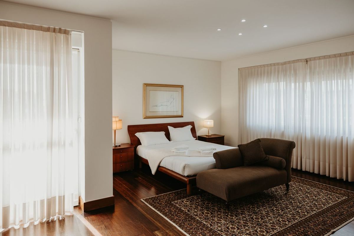 Quarto da moradia com cama preparada e roupa de cama branca