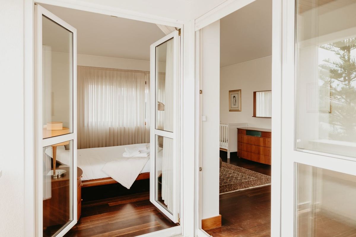 Quarto da moradia com cama preparada e roupa de cama branca