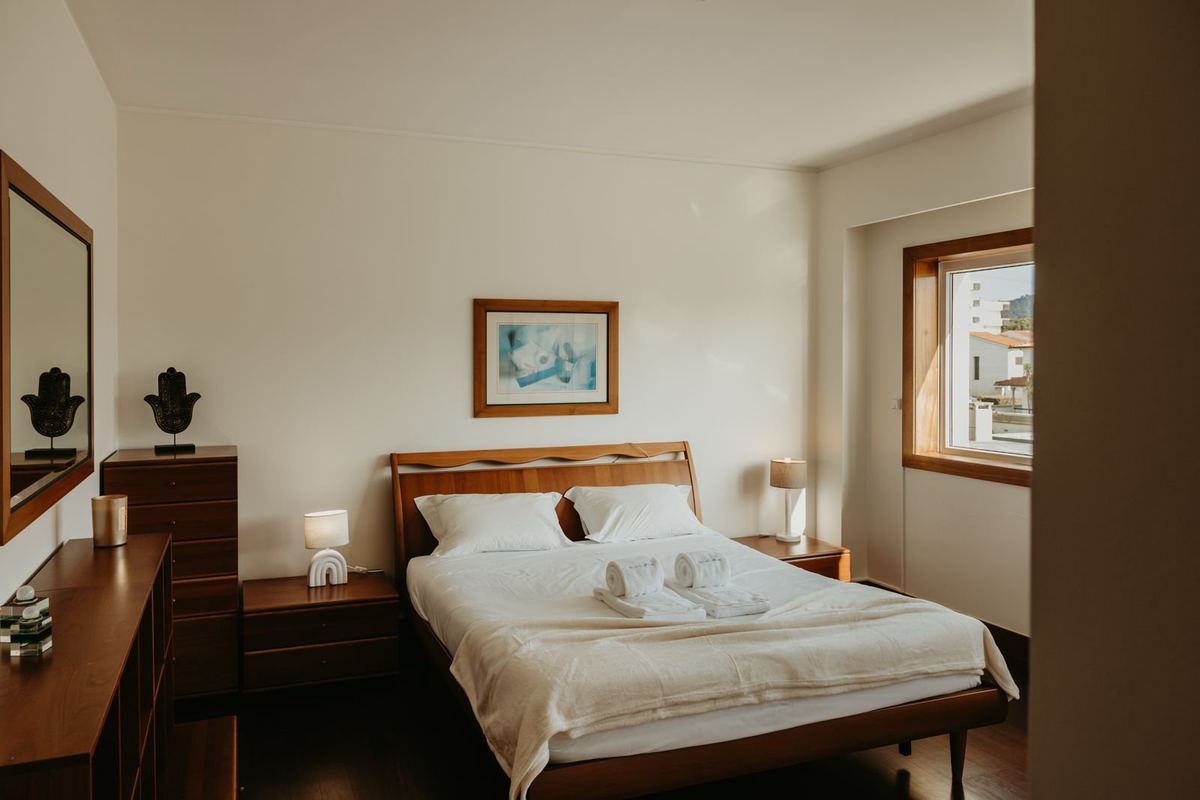Quarto da moradia com cama preparada e roupa de cama branca