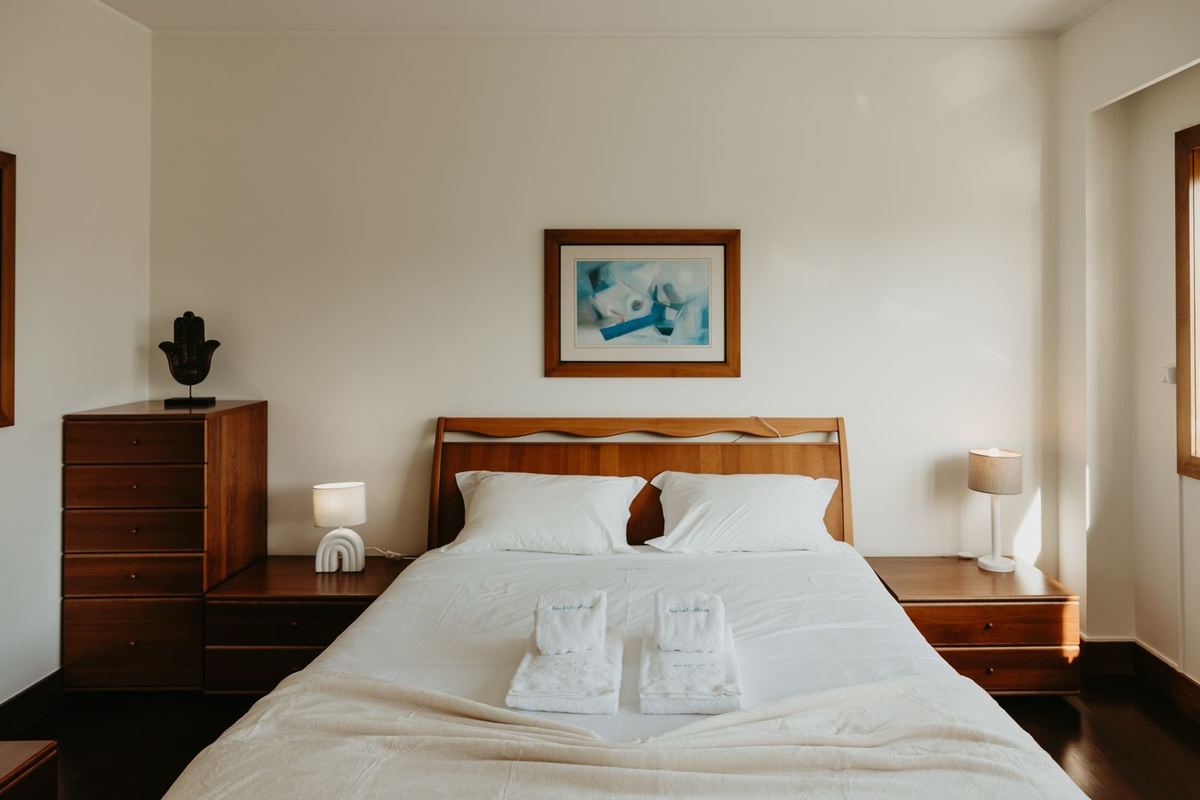 Quarto da moradia com cama preparada e roupa de cama branca