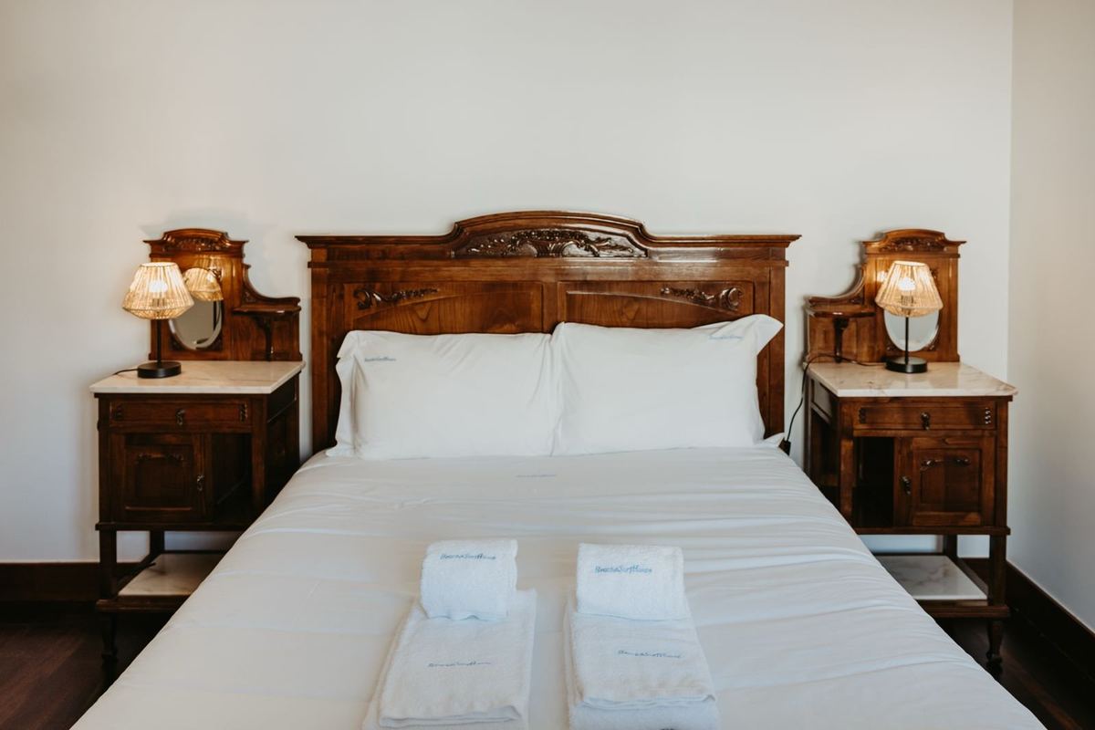 Quarto da moradia com cama preparada e roupa de cama branca