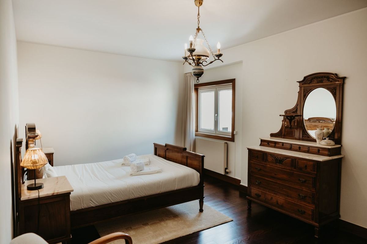 Quarto da moradia com cama preparada e roupa de cama branca