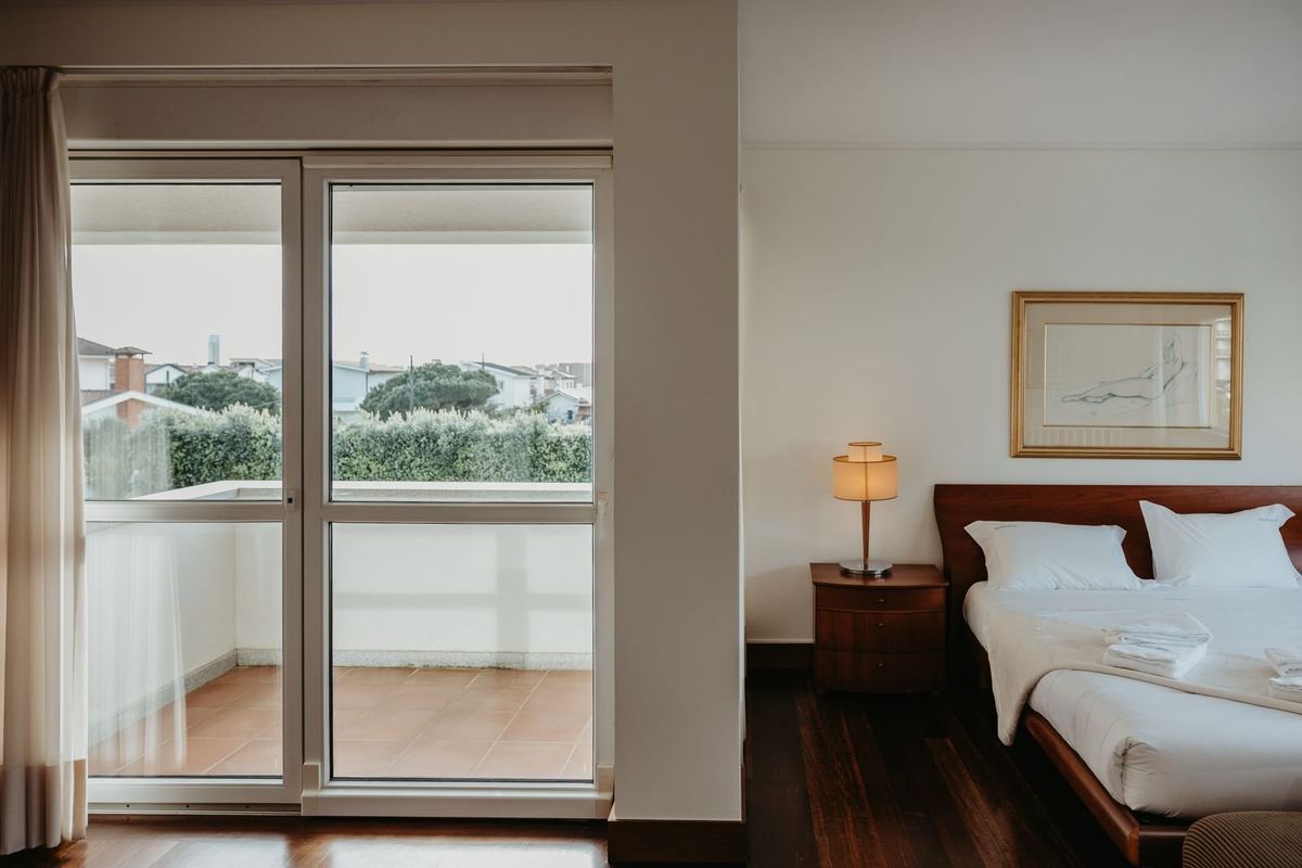 Quarto da moradia com cama preparada e roupa de cama branca