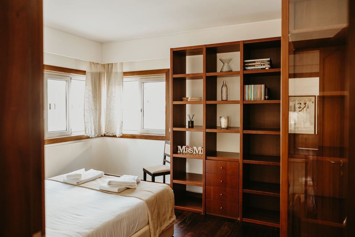 Quarto da moradia com cama preparada e roupa de cama branca