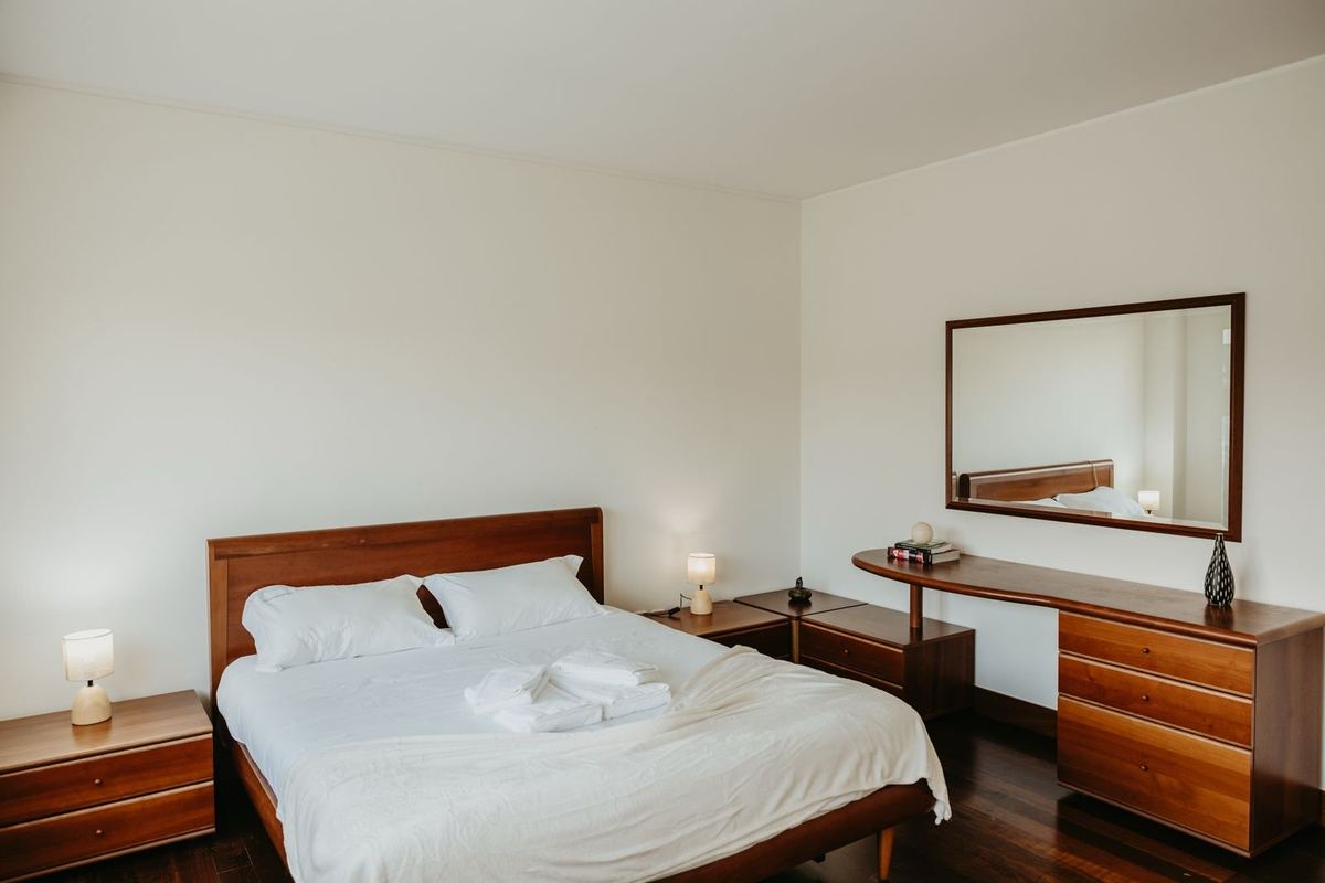 Quarto da moradia com cama preparada e roupa de cama branca