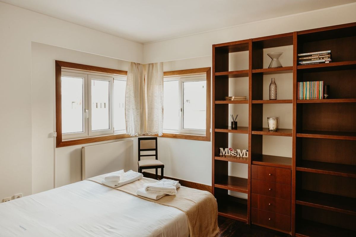 Quarto da moradia com cama preparada e roupa de cama branca