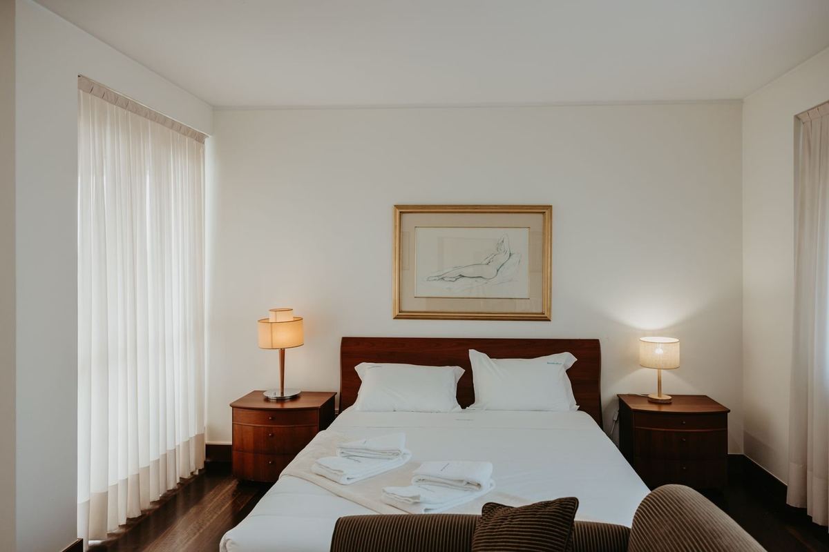 Quarto da moradia com cama preparada e roupa de cama branca